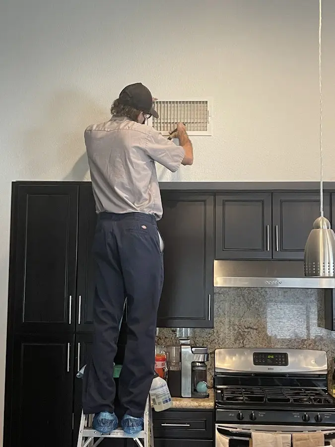 Technician inspecting an air vent during HVAC service in Saddle Brook
